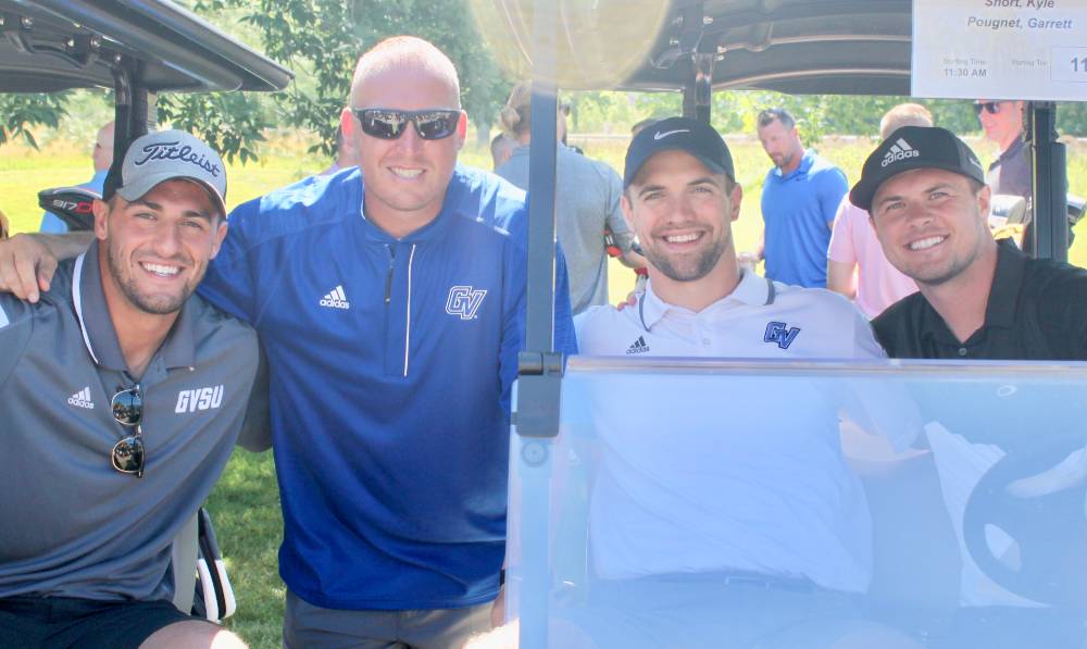 4 men in a golf cart in the sun
